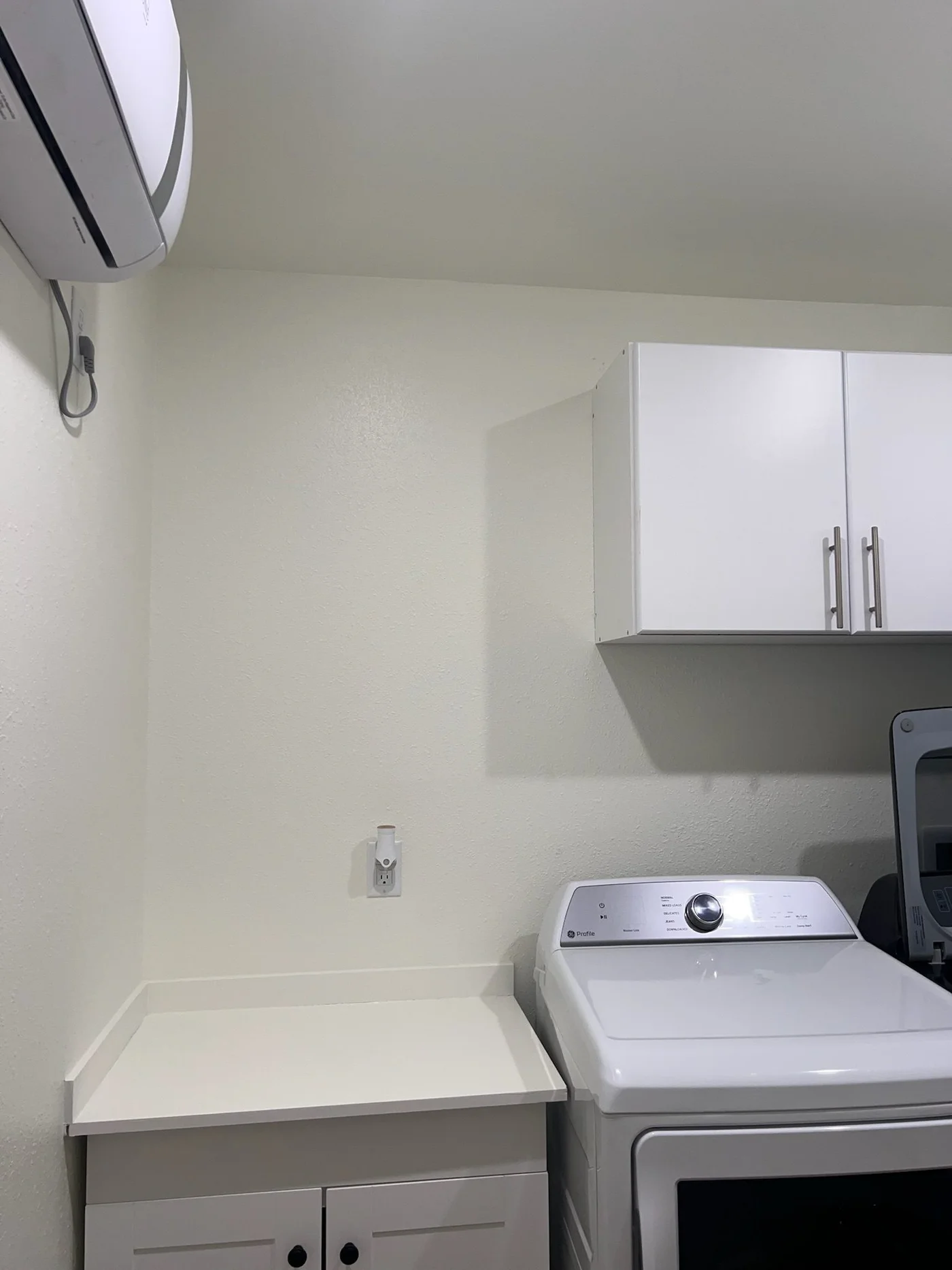 Laundry room with white upper cabinets over a washer and dryer
