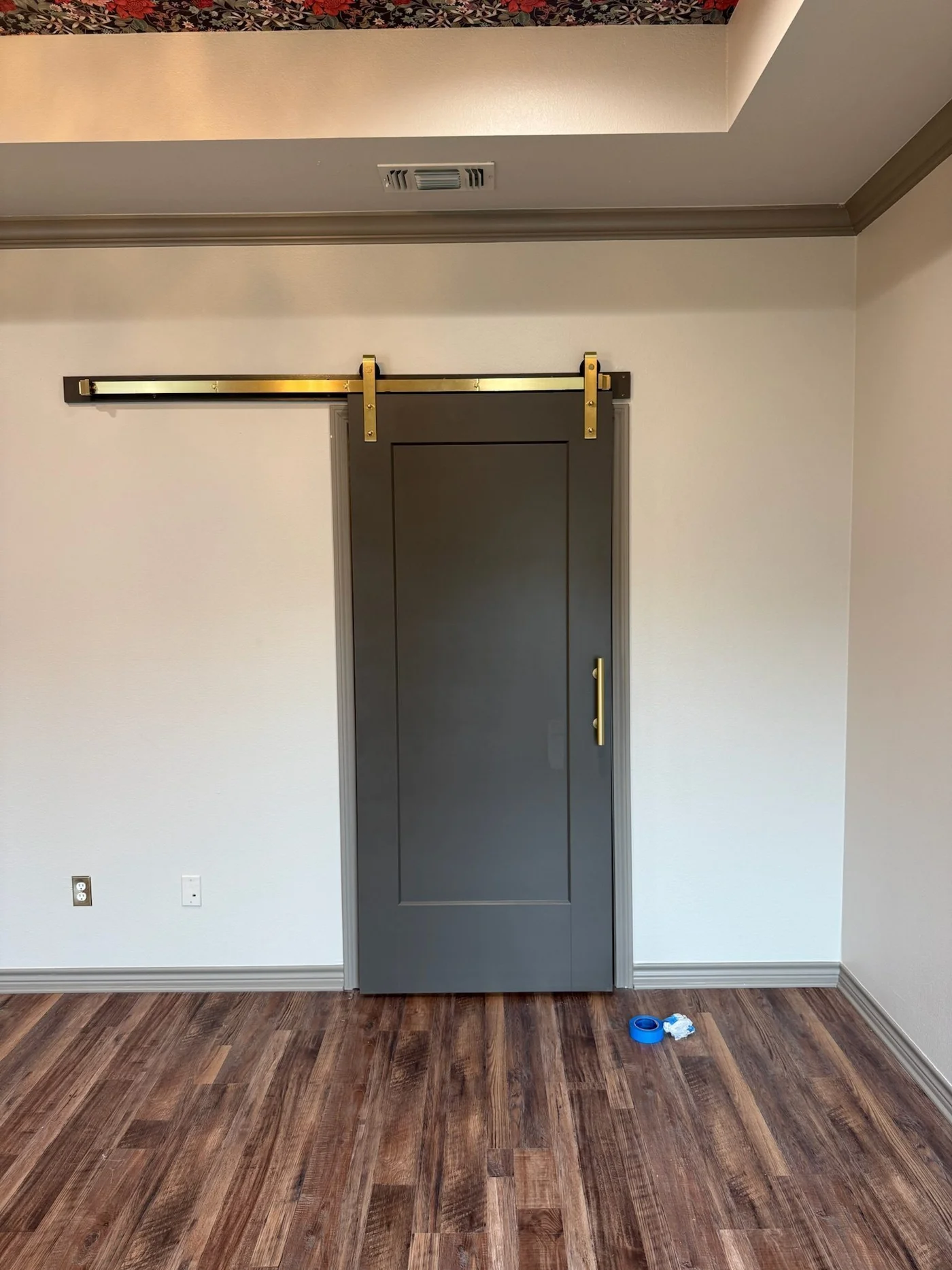 Gray barn door on brass hardware leading into primary bath