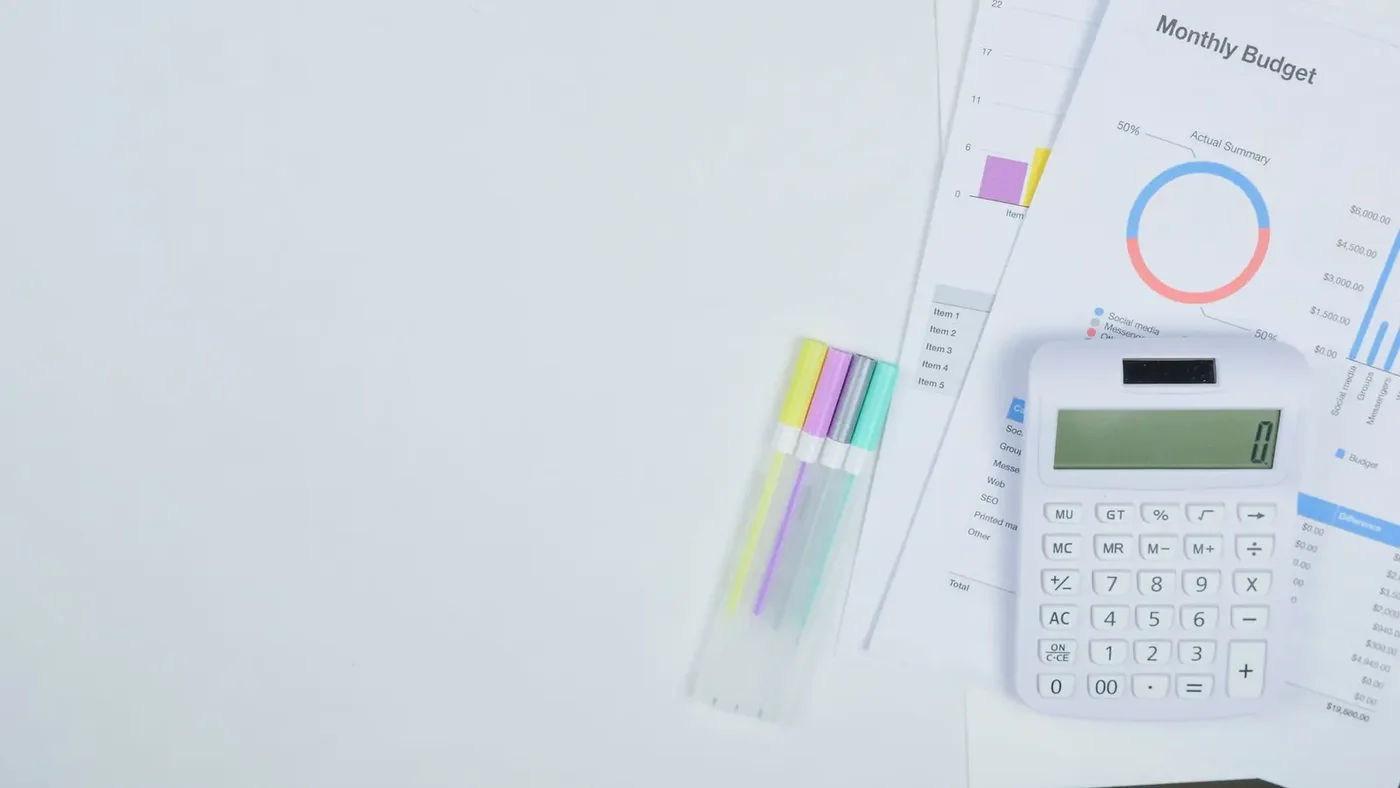 Monthly budget documents with charts and a calculator on a desk