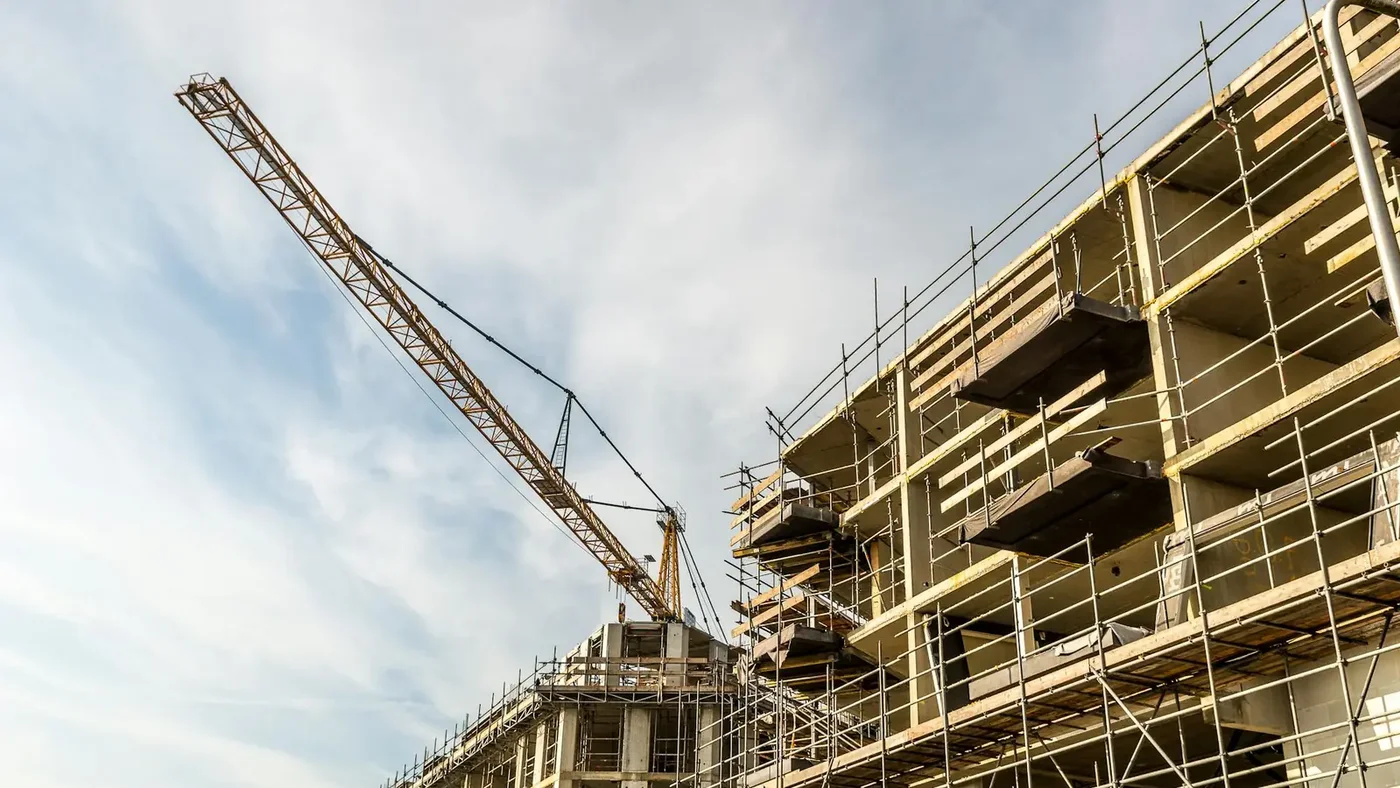 Commercial building under construction with a tall tower crane against a blue sky