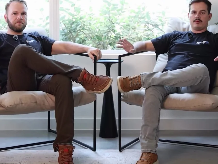 Will Christensen and Noah Brust, co-founders of Kind Roofing, seated in front of the Kind Roofing logo