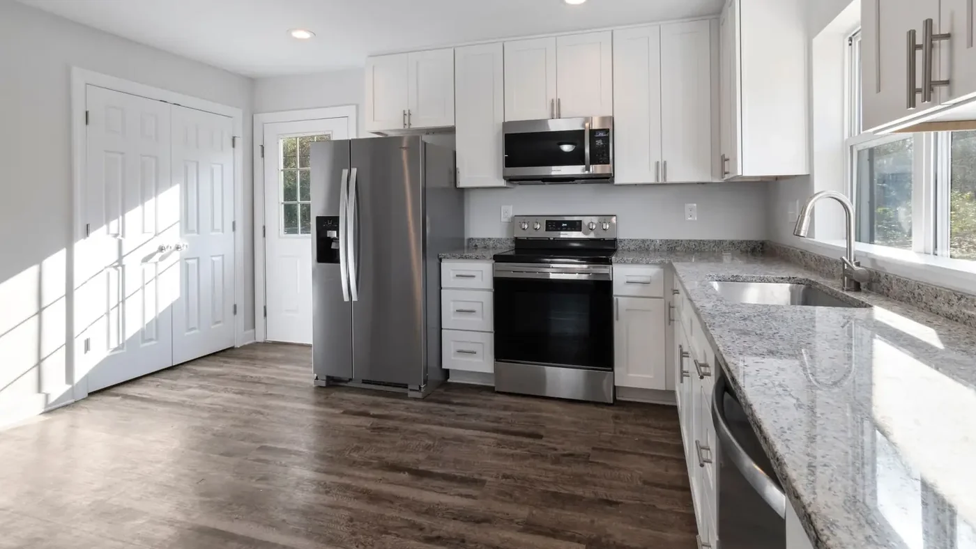 Renovated kitchen with white shaker cabinets, stainless appliances, and hardwood floors