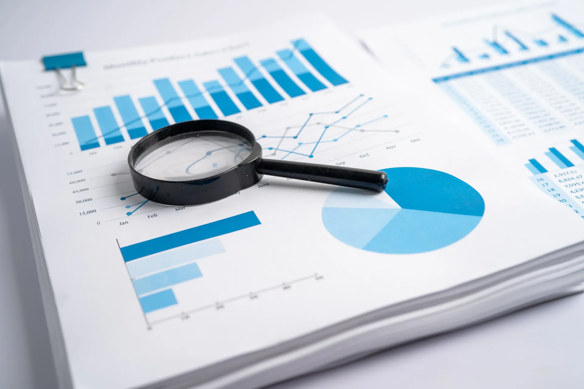 A magnifying glass held over a printed bar chart