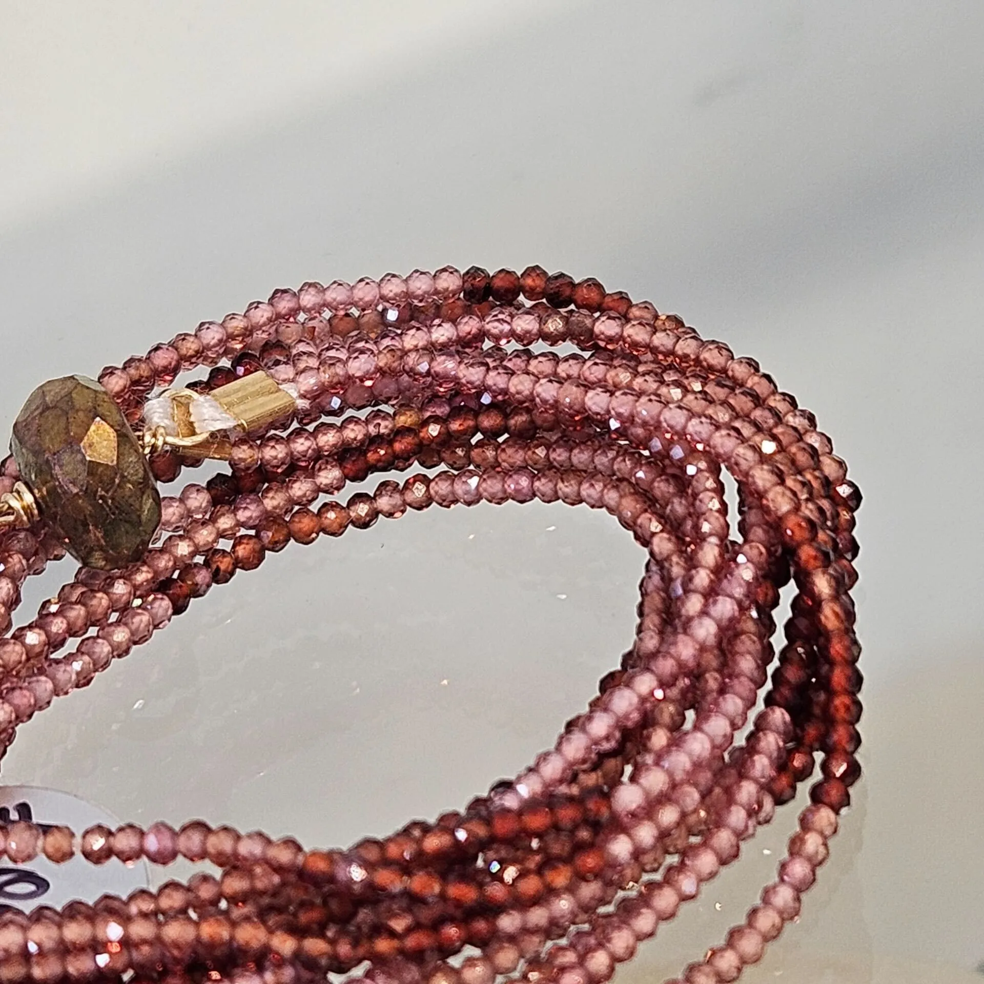 Multi-strand necklace of tiny faceted garnet beads with a gold clasp