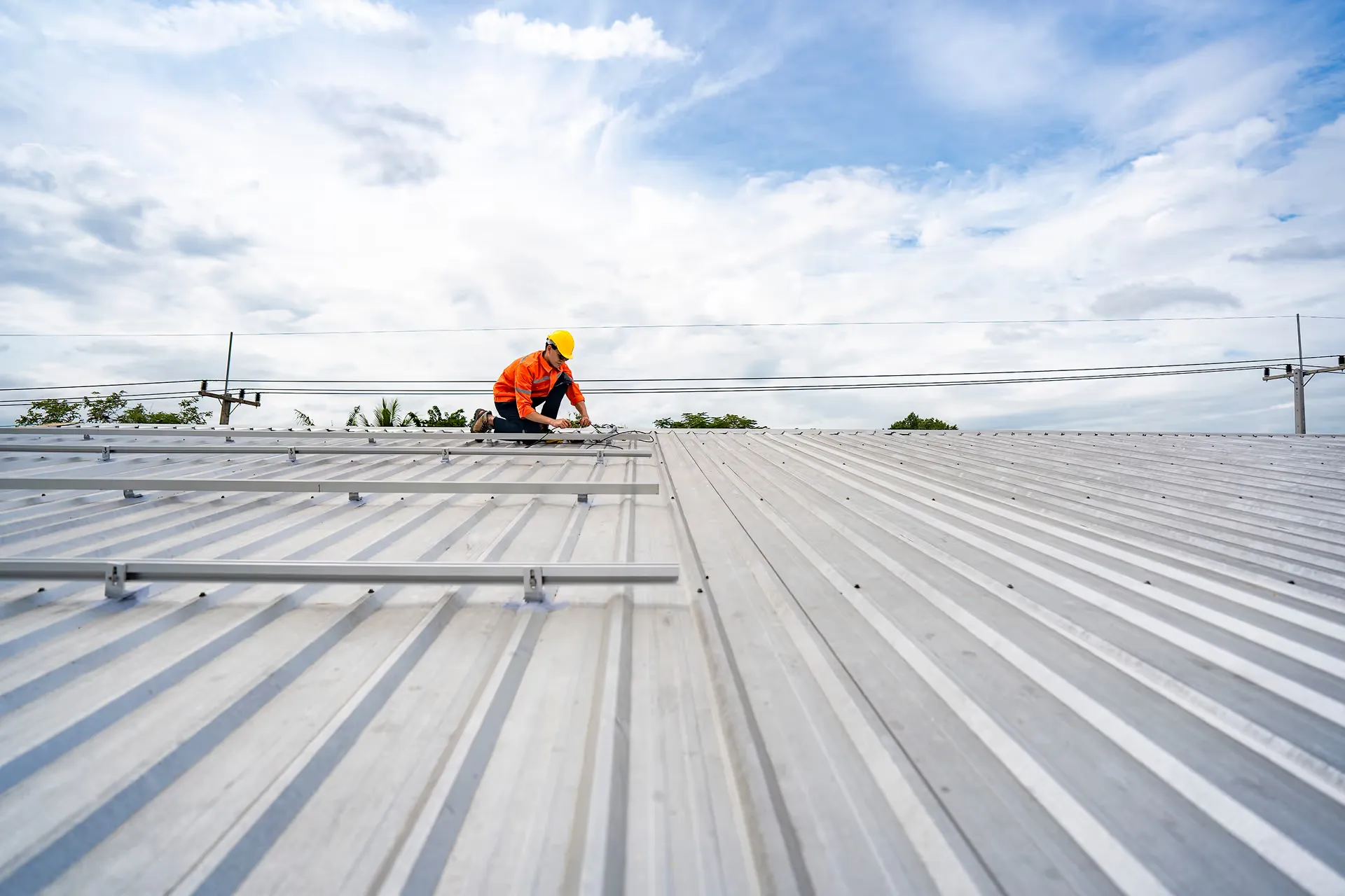 technician installing a metal roof on a commercial building